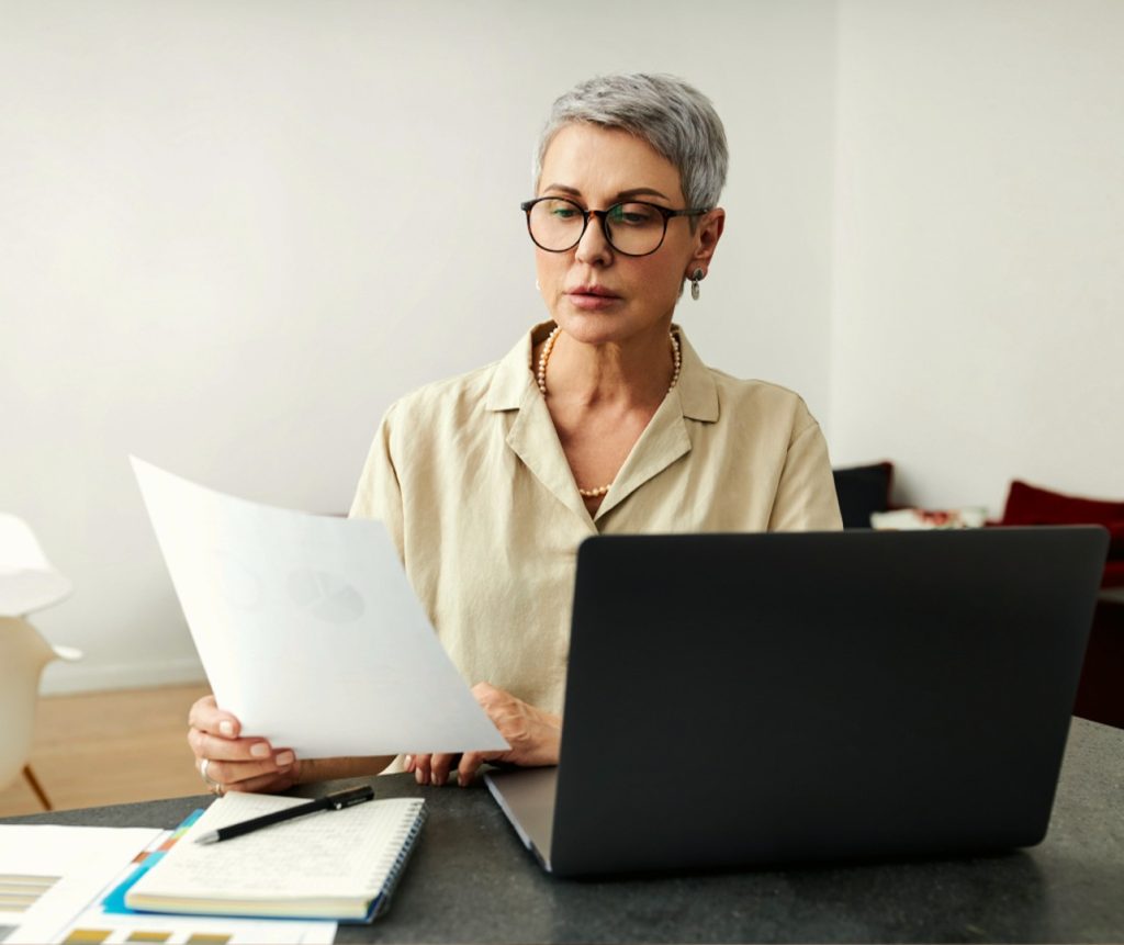 Business owner reviewing documents at a laptop